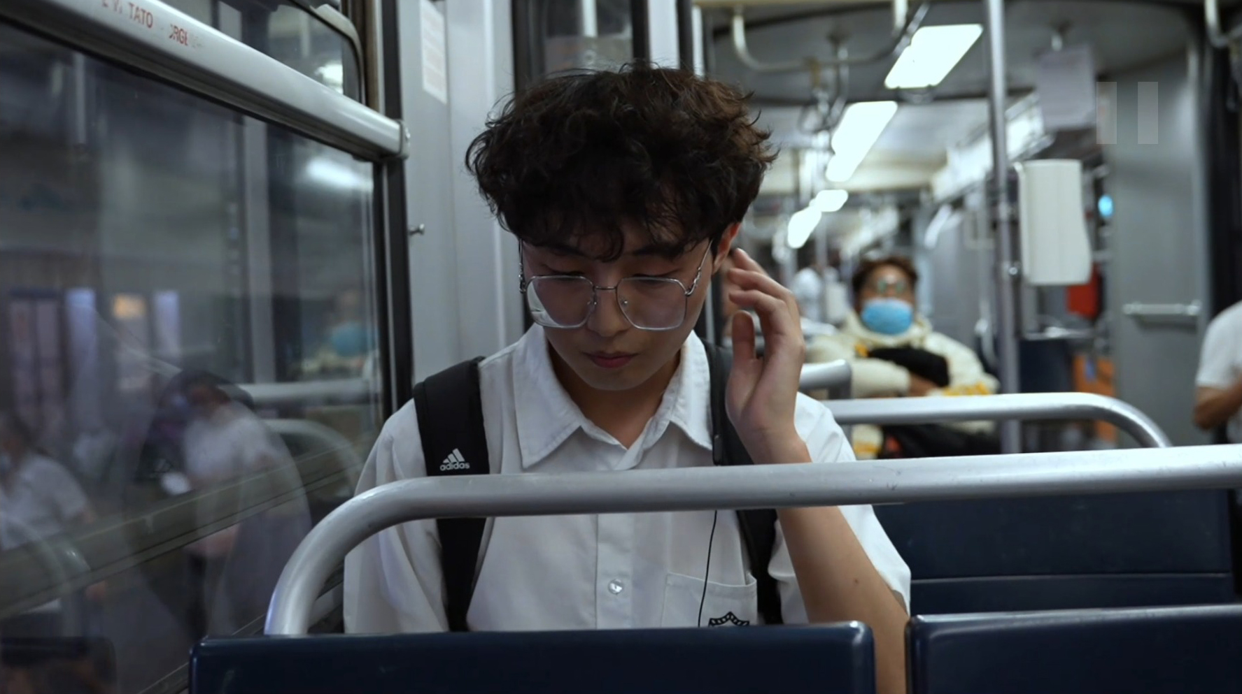 青年坐在夜间车厢内低头戴上耳机
